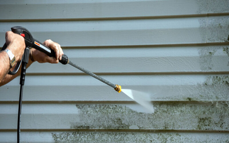 An,Unidentified,Man,Uses,A,Power,Washer,To,Clean,Mold